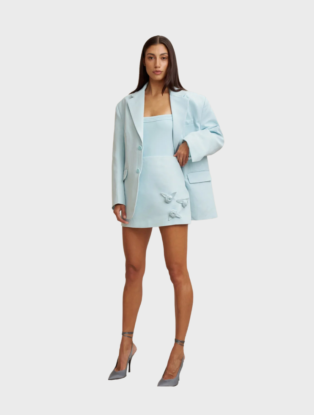 Ice blue mini skirt with an A-line silhouette, adorned with handmade rosettes, made from structured twill and fully lined.