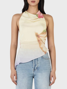 Model showcases the Iris Halter Top in Golden Drift, a yellow top with a lively floral print, perfect for warm weather.