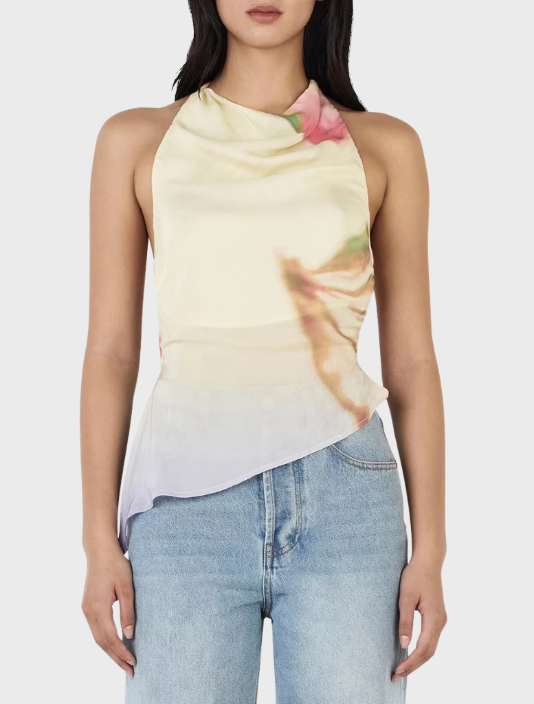 Model showcases the Iris Halter Top in Golden Drift, a yellow top with a lively floral print, perfect for warm weather.