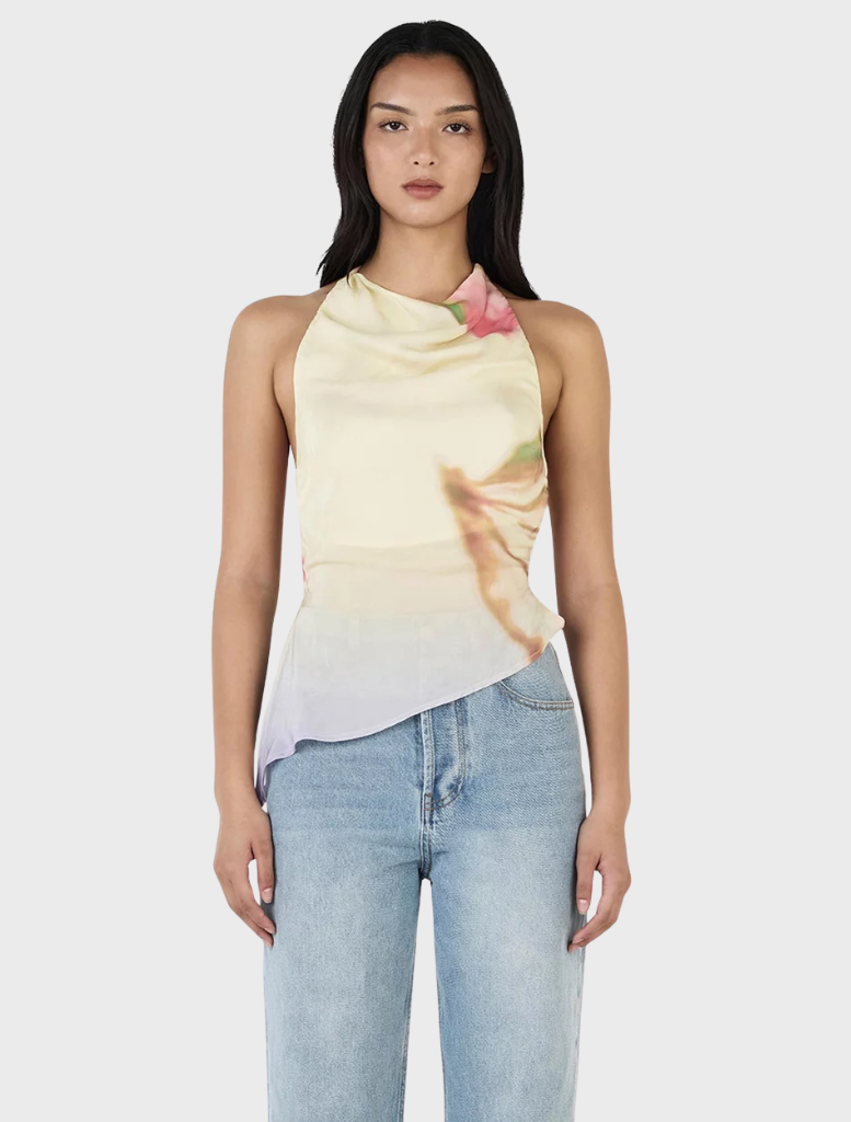 Model wearing a yellow floral print Iris Halter Top in Golden Drift, showcasing a vibrant and stylish summer look.