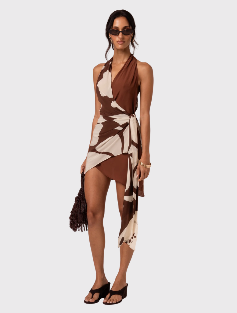 Isola Wrap Mini Dress in Ibisco has a plunging neckline, side waist tie, and an abstract floral pattern with a handkerchief hem.