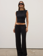 Shadowed view of a juniper top, highlighting its modern cut and sophisticated dark tones.