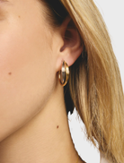 Elegant gold and silver hoop earrings arranged on a plain surface, emphasizing their stylish and modern appearance.