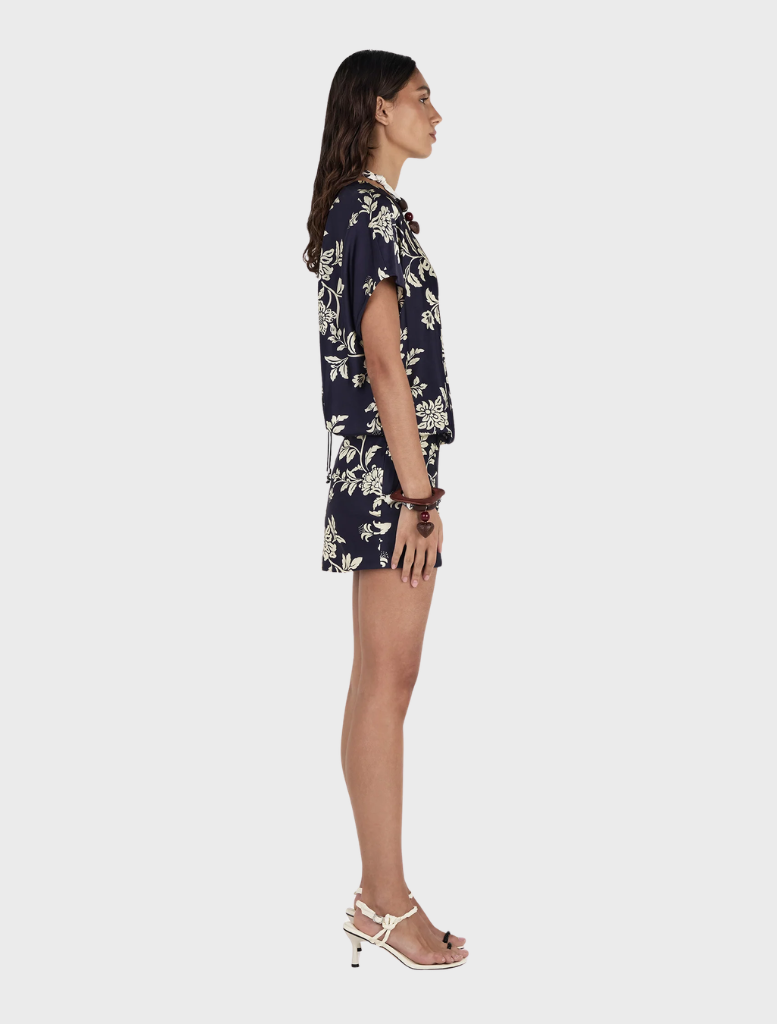 A model presents the Kodie Mini Dress, adorned with a navy and white floral pattern called Moonlit Vine.