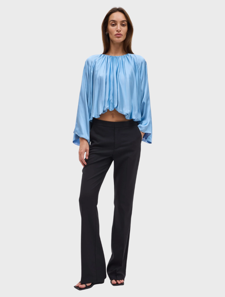 The Dreamt Blouse in lapis showcases a fluid design with gathered neckline, wide sleeves, and a softly bloused hem for comfort.