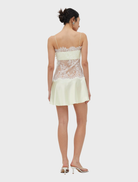 Fitted lemonade lace mini dress with rouleau straps, flared skirt, and side closure, combining structure and lightness.
