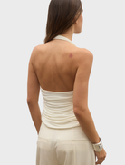 A woman models a white Lennie top paired with wide pants, presenting a trendy and casual outfit choice.