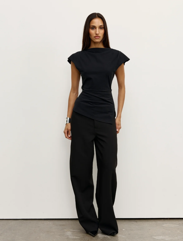 Black Liana top displayed on a hanger, showcasing its sleek design and fabric texture.