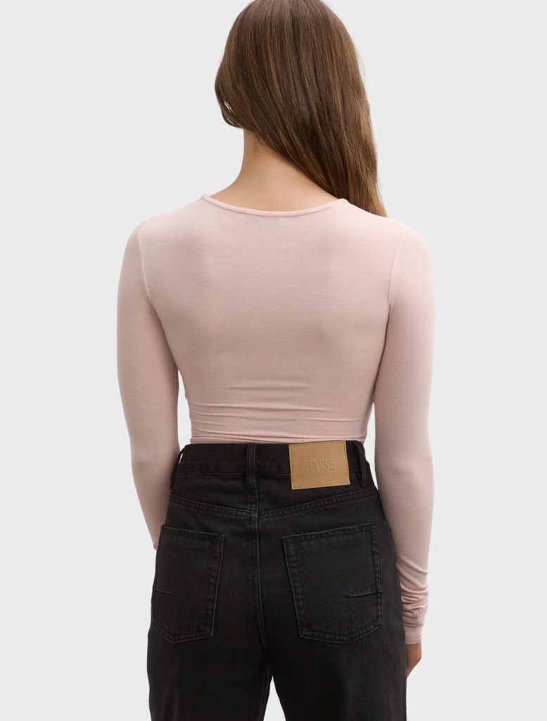 Back view of a woman wearing a pink ballet-lila bodysuit, showcasing the design and fit of the garment.