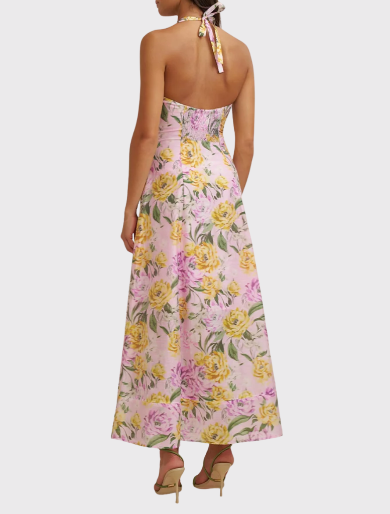 A model displays a lilac floral sundress featuring a halter neck, sleeveless style, and midi length, perfect for warm weather.