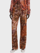 Long orange trousers featured against a neutral backdrop, emphasizing their bold color and relaxed fit for casual outfits.