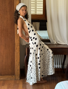 A woman wearing a polka dot dress poses in front of a mirror, looking at her reflection with a smile.