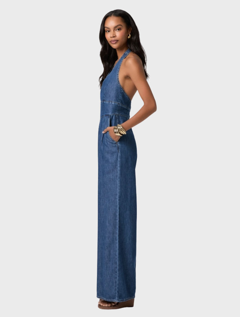 The Marilyn Jumpsuit showcases a vintage-inspired design with a halter neck, wide legs, and lightweight dark wash denim.
