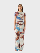 A woman models the Marley Mesh Tee in Playa, featuring vibrant abstract designs on a casual t-shirt.