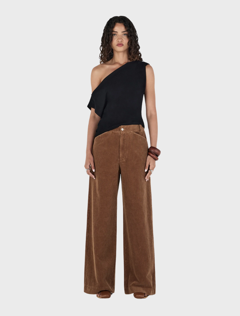 Tan Max Cord Pants displayed on a wooden surface, showcasing their soft texture and classic design.