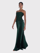 The Maya Gown showcases a strapless silhouette, elasticated bodice, and pleated skirt, combining comfort with sophistication.