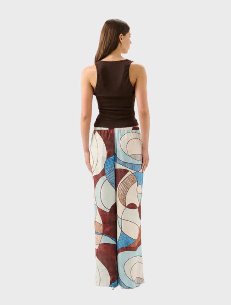 A woman showcases the Miles Pant in Playa, characterized by its distinctive and colorful pattern.