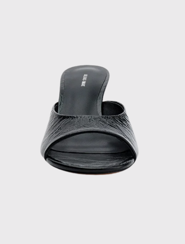 Elegant open-back mule in black leather with a wide strap and sculptural wedge heel, perfect for casual or dressy occasions.