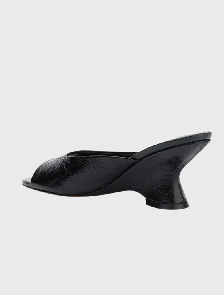 Black leather slip-on mule with a wide strap, round toe, and a 75mm wedge heel, designed for comfort and elegance.