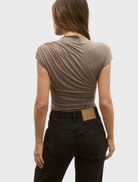 Back view of a woman in a mink Astrid bodysuit paired with jeans, showcasing a stylish and casual outfit.