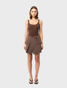 Mocha Vault Mini Skirt draped elegantly, emphasizing its modern cut and rich color on a plain surface.