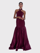 Montaigne Gown in wine, featuring a high halter neckline, fitted silhouette, and flared hem for elegant movement and structure.