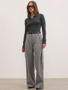 A model dressed in grey trousers paired with a black top, presenting a modern and versatile fashion look.