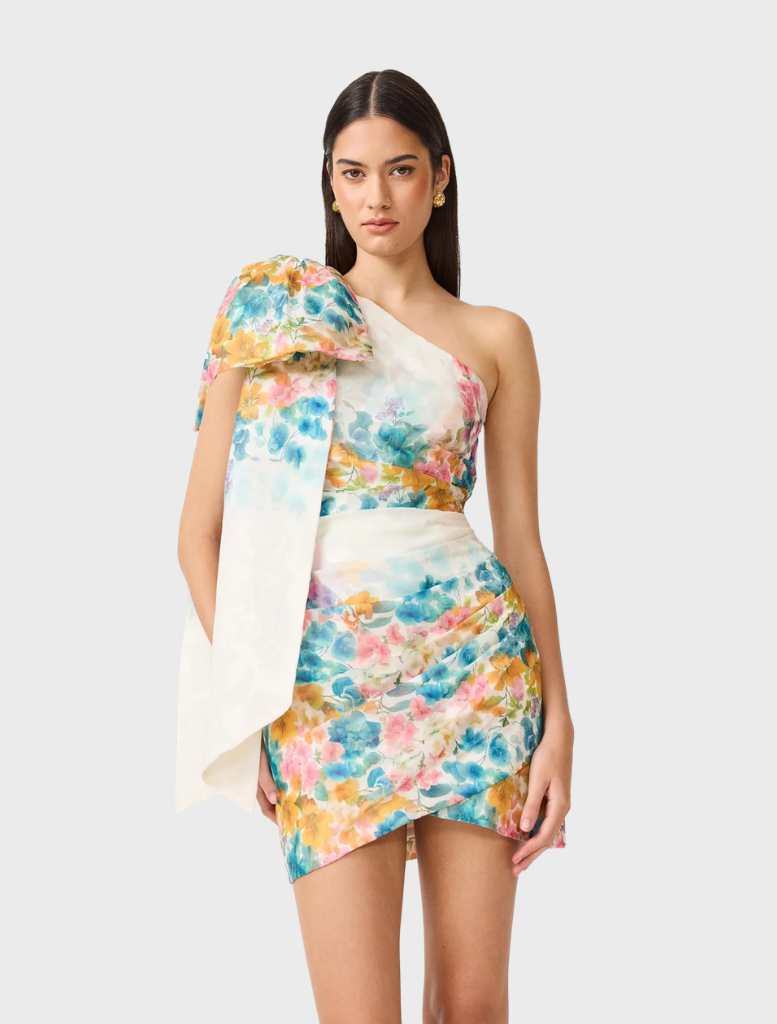 A vibrant multi floral one-shoulder mini dress, featuring a fitted silhouette and playful floral patterns, displayed elegantly.