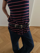 A woman dressed in a navy blue coat and hat poses for a selfie, smiling brightly.