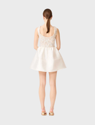 Stylish A-line mini dress in white and gold, featuring a structured bodice and a flared skirt for a fashionable silhouette.
