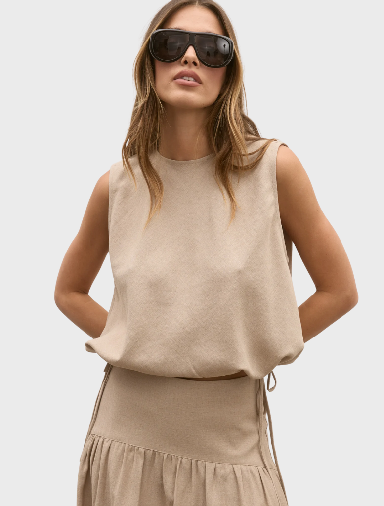 A model displays a nude Delphine top paired with a matching skirt, highlighting a chic look.