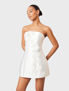 Strapless white maxi dress adorned with a colorful oleander floral design, suitable for outdoor gatherings and parties.