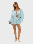 A woman dressed in a blue short skirt and blouse, highlighting a trendy summer fashion choice.