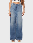 A woman wearing wide-legged jeans and a striped top stands, representing a chic and casual fashion choice.
