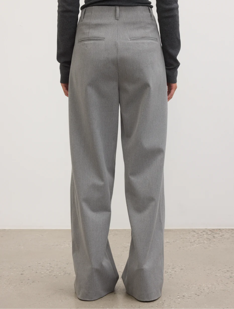 Back view of a woman wearing grey trousers, showcasing a stylish and modern outfit.