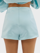 A woman in a pale blue short skirt paired with a blouse, representing a fashionable summer ensemble.