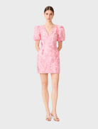 Elegant pink mini dress with puff sleeves and a flared silhouette, designed by Monique for a stylish, feminine look.
