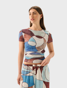 A woman wears the Marley Mesh Tee - Playa, displaying unique abstract designs on a comfortable t-shirt.