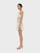 A lemon-colored lace mini dress with a structured bodice, delicate straps, and a flared skirt, featuring a discreet side closure.