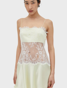 Lemonade-colored mini dress with lace overlay, fitted bodice, rouleau straps, and a flared skirt, finished with a side closure.