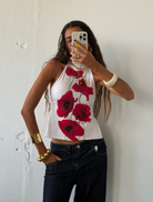 A woman smiling while taking a selfie in front of a plain white wall.