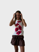A woman stands in front of a white wall, 