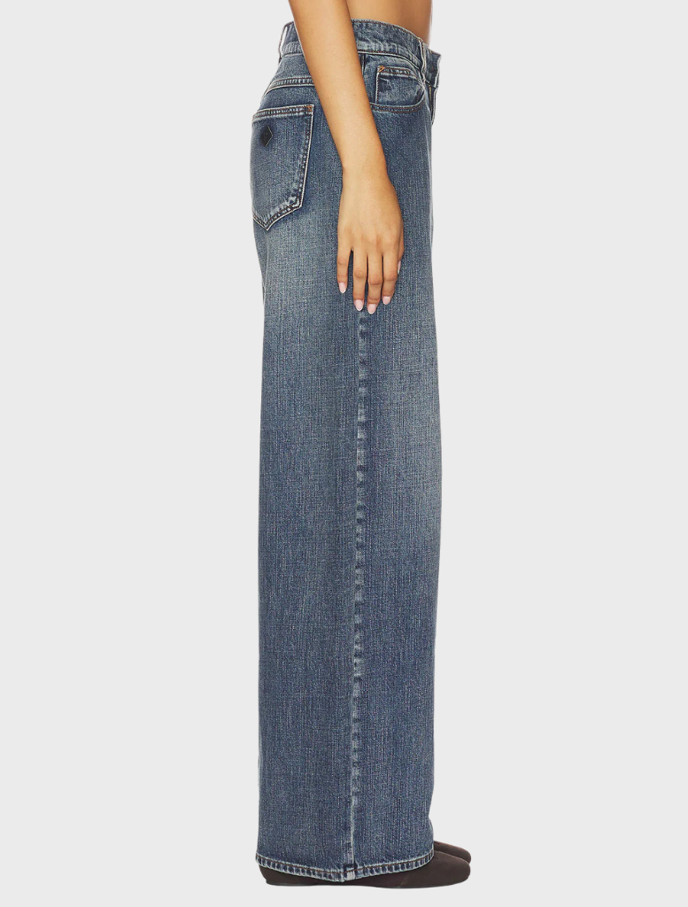 A close-up of the 95 Super Baggy jeans, emphasizing the fabric texture and relaxed silhouette in a bright, modern environment.