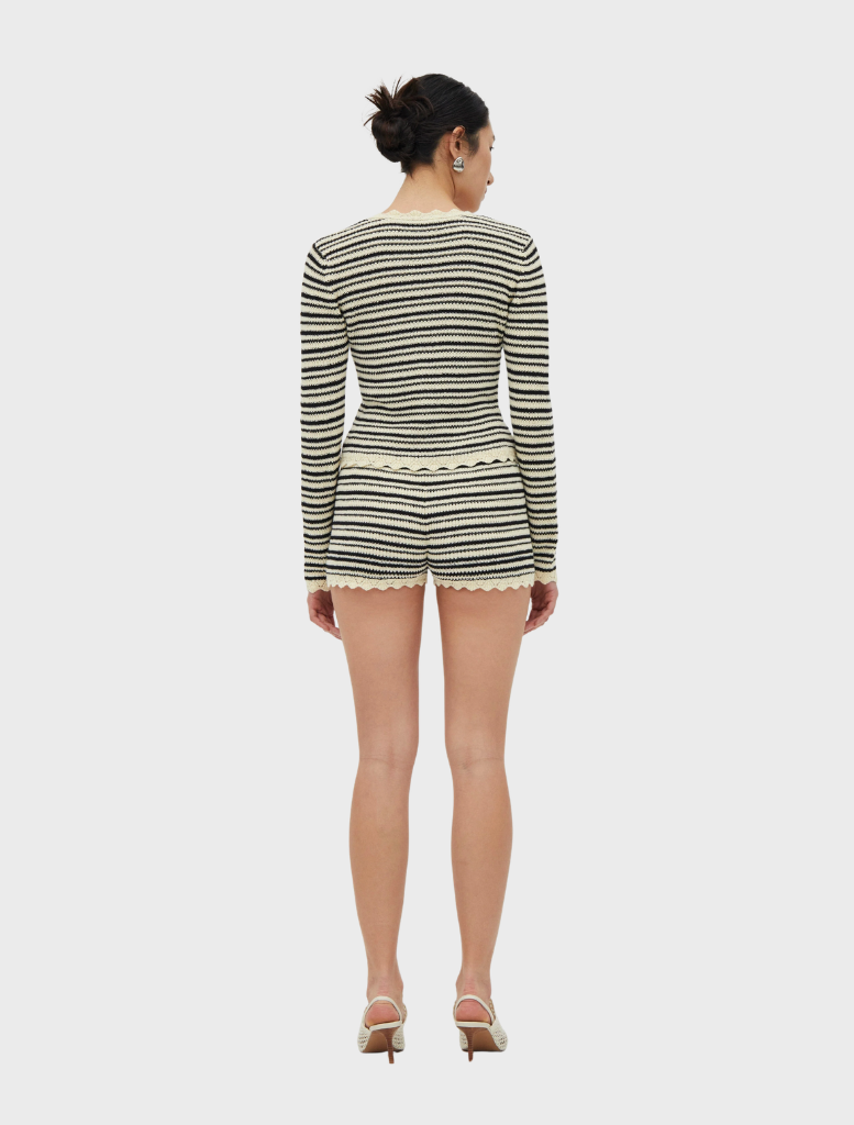 A cream and coffee Resonance knit cardigan draped elegantly, highlighting its cozy fabric and modern silhouette.