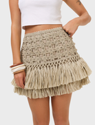  Natural-colored Riley Raffia Skirt displayed on a mannequin, showcasing its textured design and flowing silhouette.