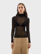 Black Riley top displayed on a hanger, showcasing its sleek design and fabric texture.