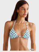 A blue polka dot Rio top hanging, featuring a playful pattern and modern cut, perfect for casual wear.