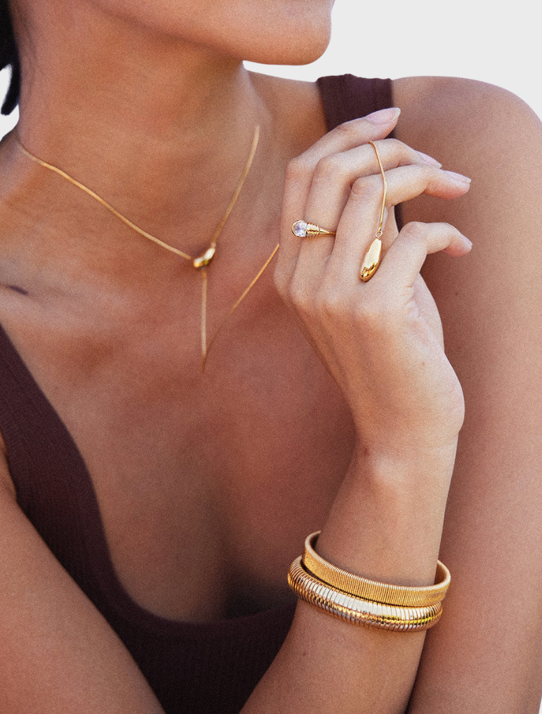 Sabrina's gold cuff bracelet, characterized by its contemporary style and polished surface.