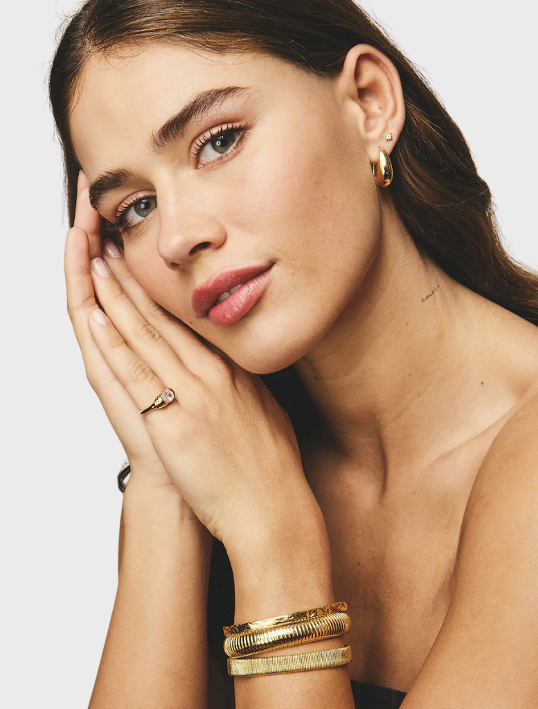 Elegant gold cuff by Sabrina, featuring a minimalist design that highlights its luxurious finish.