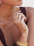 A gold cuff bracelet designed by Sabrina, showcasing a sleek and modern aesthetic.